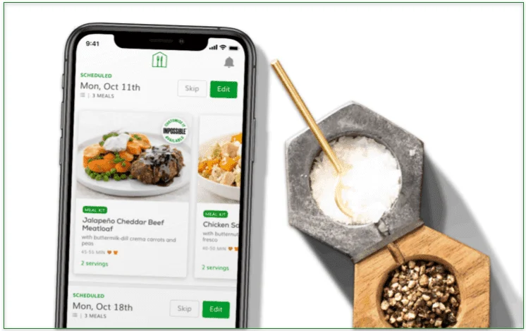 Image of Home Chef's app displayed on a phone screen next to a salt and pepper pot