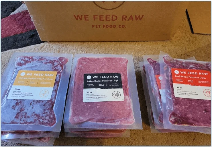 Packs of 3 different recipes in front of a We Feed Raw delivery box