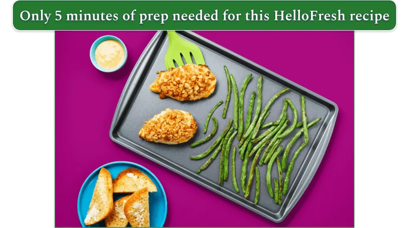 Image of ingredients on a baking sheet next to some garlic bread to serve from HelloFresh