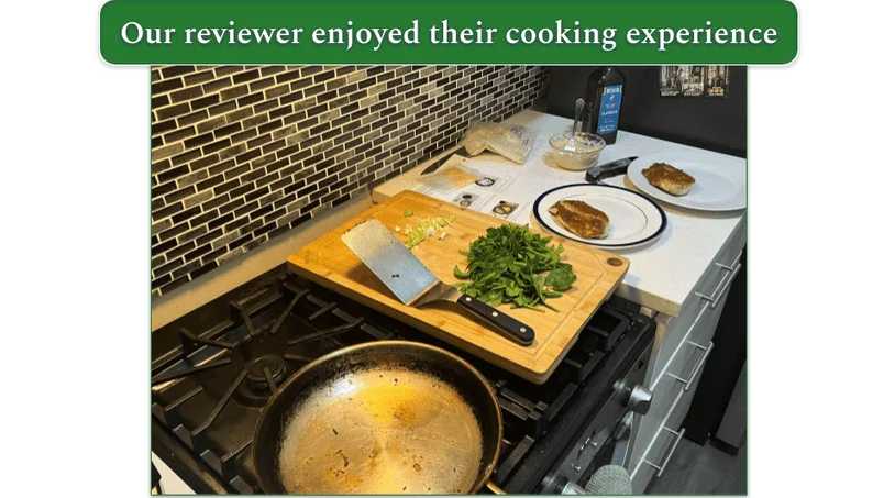 Image of a pan on the stove with a plate next to it with crispy chicken on it and a chopping board with greens