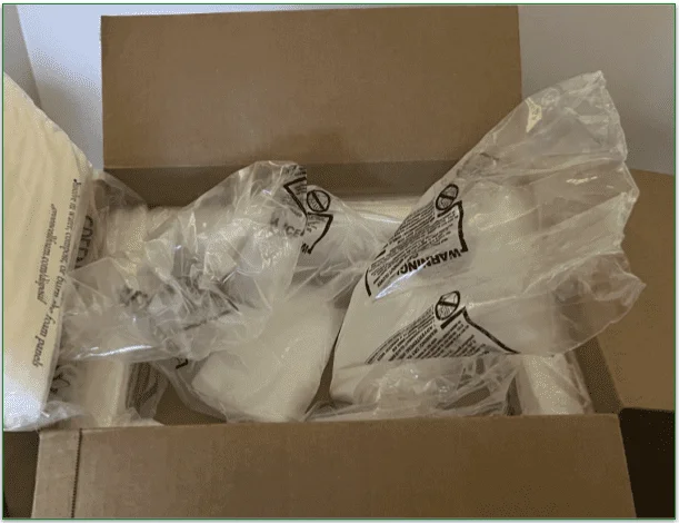 Photo of an open BistroMD box containing packs of dry ice with warning labels on
