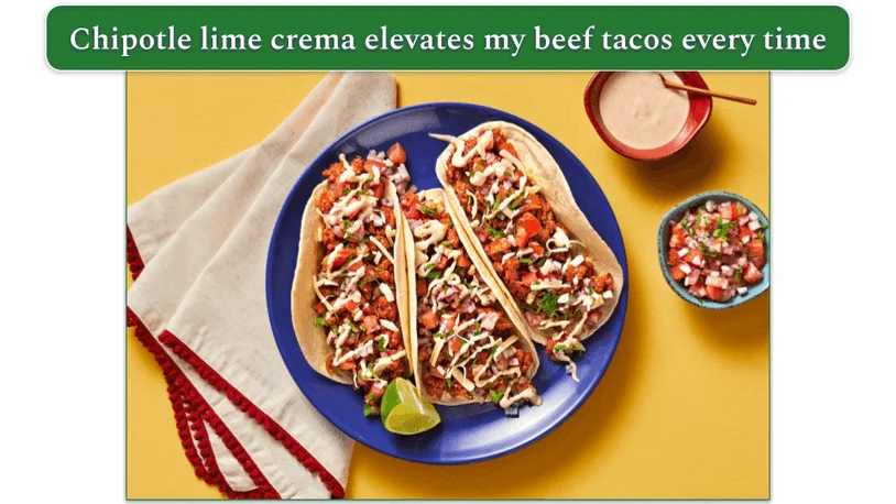 3 beef tacos topped off with chipotle lime crema on a round wooden serving plate.