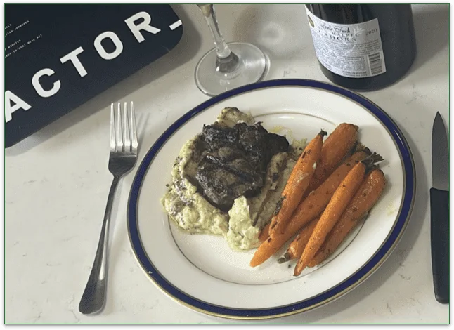 Image of the Truffle Butter Filet Mignon on a plate ready to eat with a wine glass and bottle of wine next to it