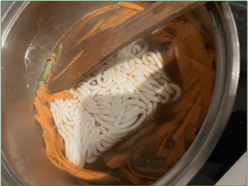 Image from our reviewer of a pot containing carrots, noodles, and broth whilst making miso noodles