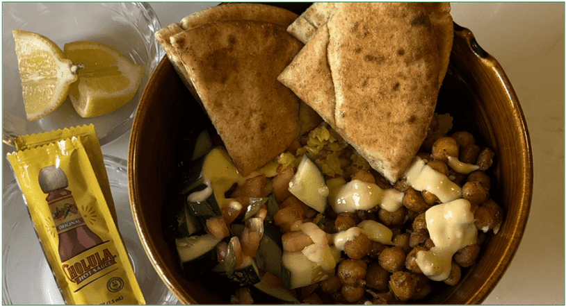 Photo of HelloFresh's Street Cart-Style Chickpea Bowls dish served in a bowl with hot sauce and lemons on the side