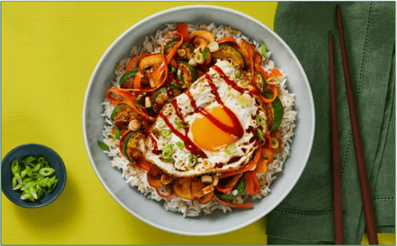 a bowl of vegetables and rice with a sunny-side egg on top