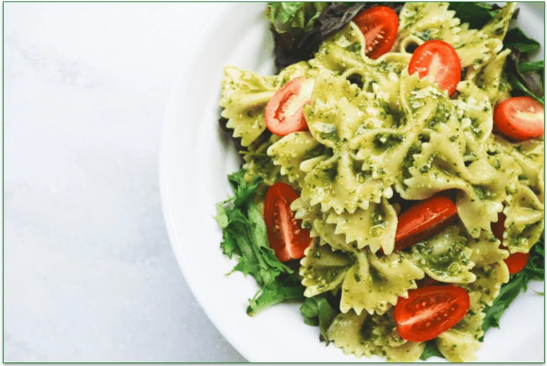 Bowl of farfalle pasta with greens and tomatoes