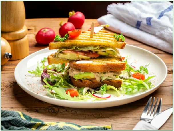 A tuna melt on a plate with some salad.