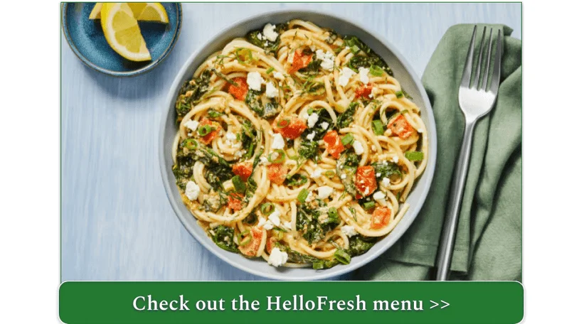 A bowl of spaghetti with chopped tomatoes, greens, and feta cheese