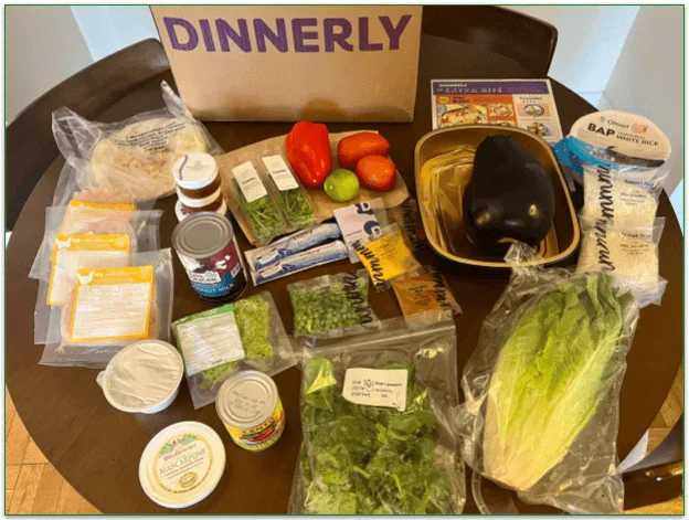 Image of a Dinnerly box in a table with various ingredients set out in front of it