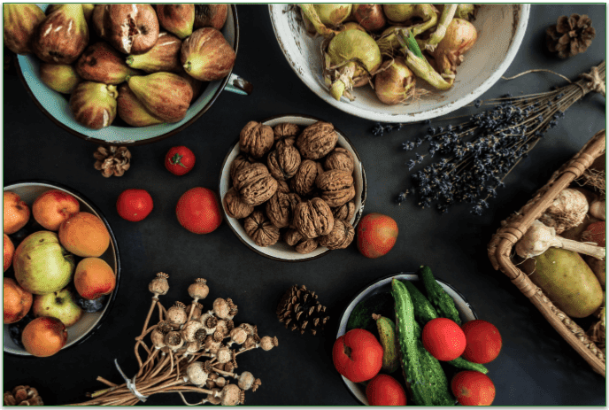 A variety of whole foods, including nuts, fruits, and veggies, on a table.