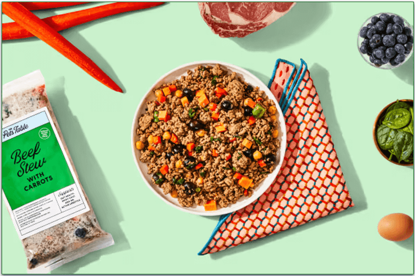 Image of a bowl of Beef Stew next to a full pack of Beef Stew recipe and some of the fresh ingredients used in the recipe