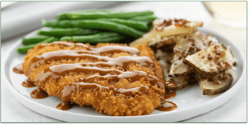 A plate of fried chicken with roasted potatoes and green beans