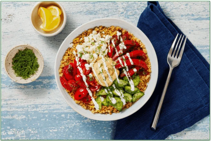 A bowl of couscous, veggies, and hummus.