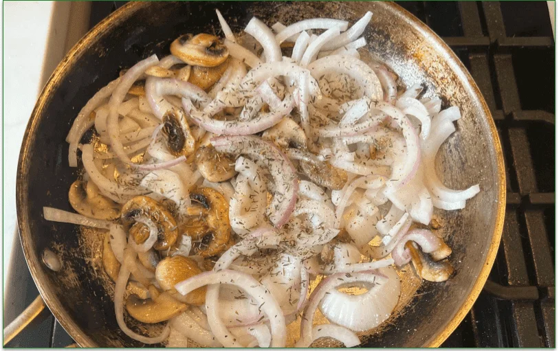 Frying pan with sliced onions and mushrooms