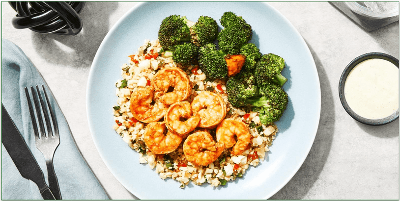 A plate of shrimp with cauliflower rice and broccoli