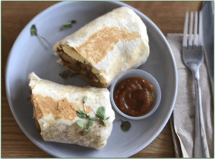 A sliced burrito served with salsa on a plate
