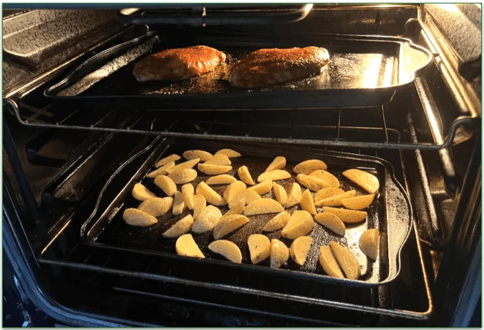 Chicken breast and potato wedges cooking in the oven