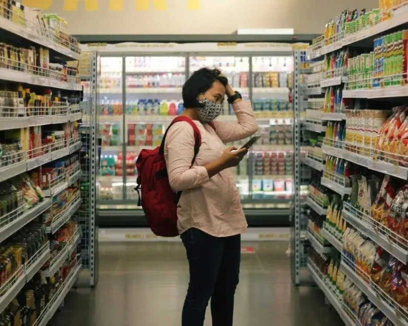 Woman in a supermarket, trying to figure out which products to buy
