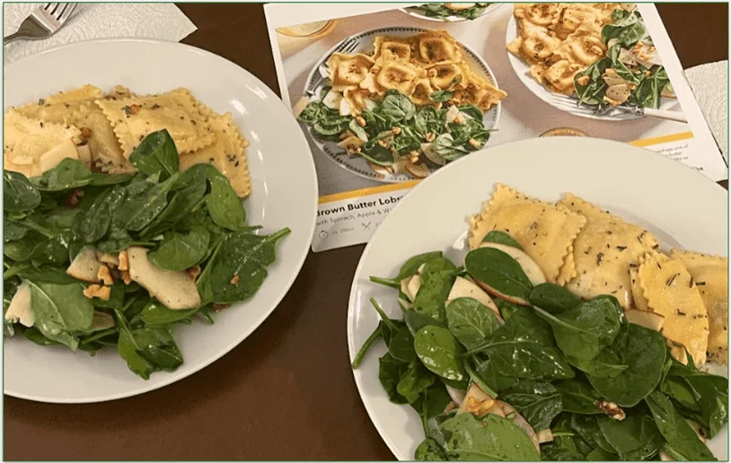 Photo of Marley Spoon's Chicken Karaage recipe card held behind the cooked dish served on a board with wedges and mayo