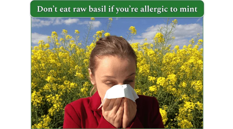 A lady wiping her nose in the forefront while blossoming plants are in the background