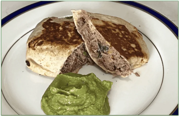 Photo of TRifecta's Brisket Burrito with Guacamole served sliced in half on a plate