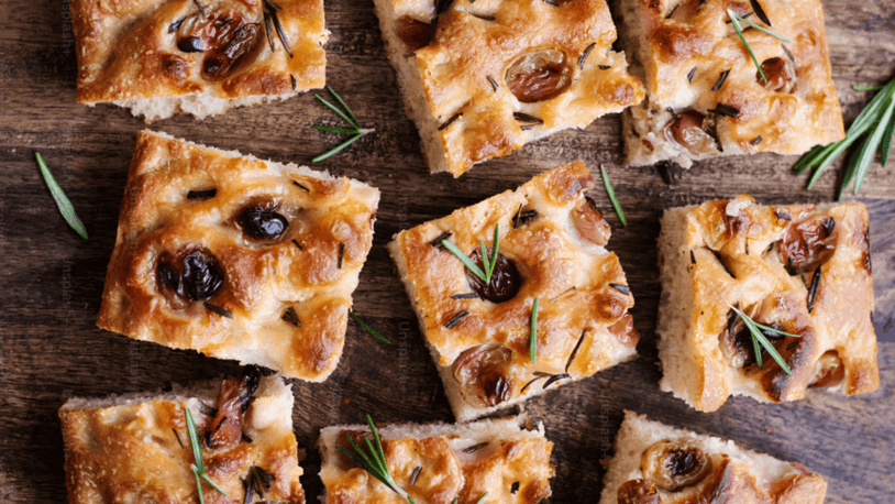 Several pieces of focaccia on a wooden table.