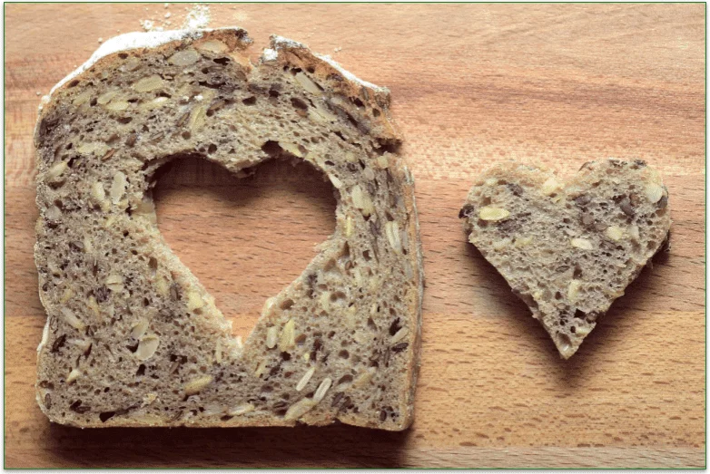 Slice of whole grain bread with a heart cut from the center and placed next to it