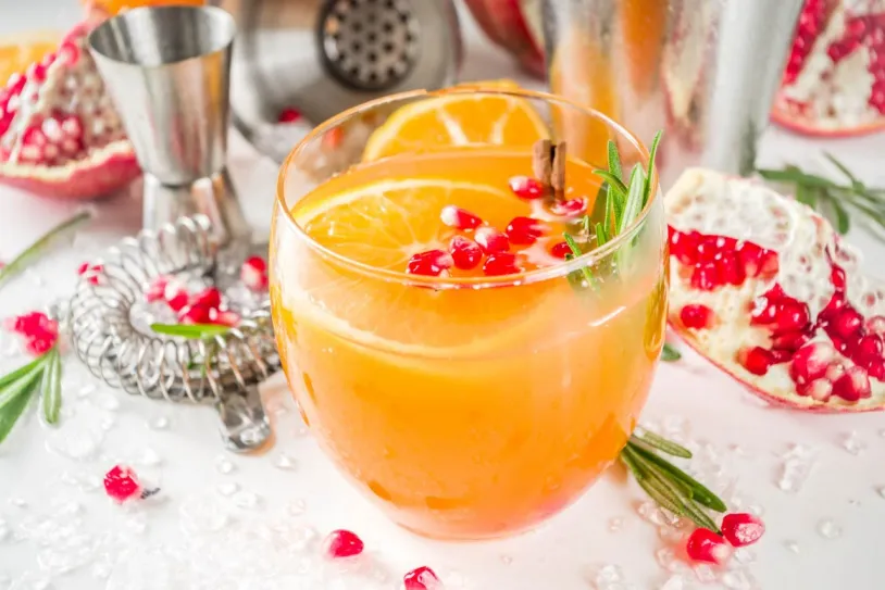 Orange and rosemary fizz surrounded by christmas decorations