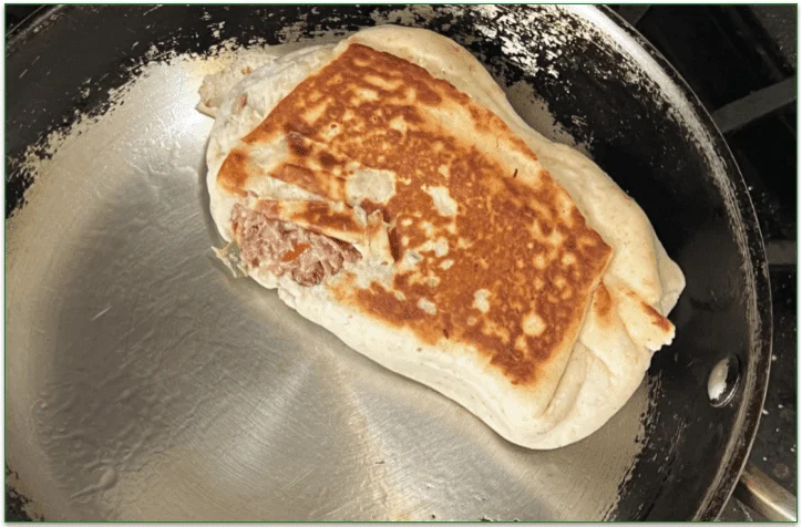 Photo of a crispy burrito being heated in a skillet