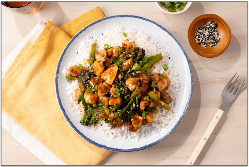 A plate of chicken and vegetables over rice
