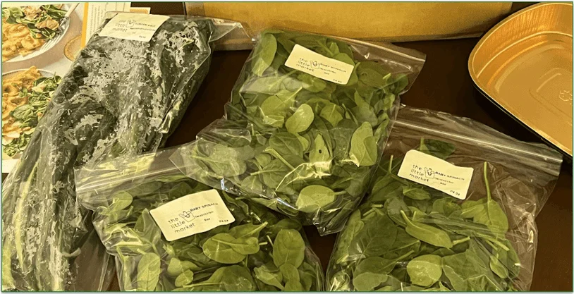 Photo of bags of fresh leafy greens next to a Marley Spoon delivery box and recipe cards