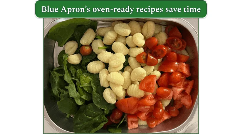 Raw tomatoes, spinach, and gnocchi in a baking tray
