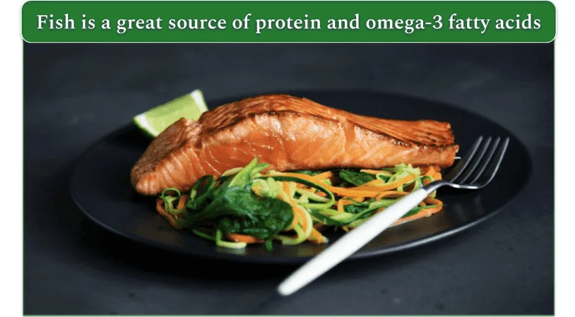 Fish fillet and veggies on a black plate.