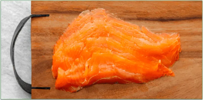 Rastelli's sustainably-raised, cold-smoked, thinly sliced salmon on a wood cutting board.