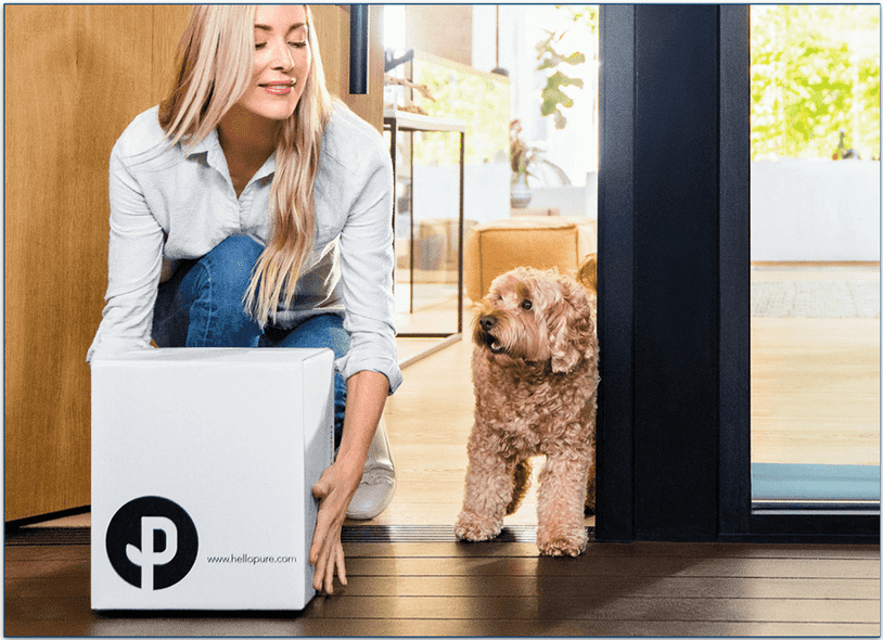 Woman and dog collecting a Pure Dog Food delivery box from the doorstep