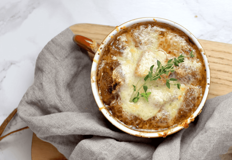 Bowl of French onion soup with a cheesy topping and herbs