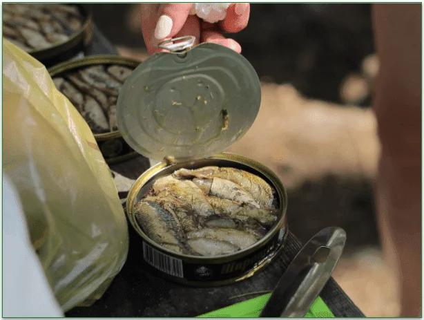 A woman opening up a can of canned fish.