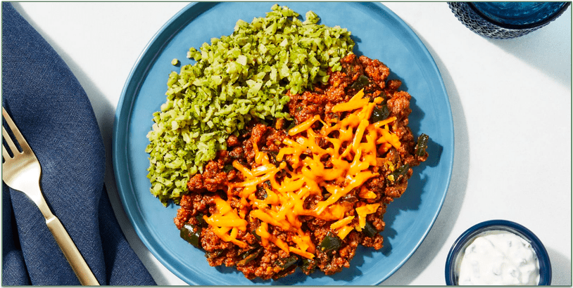 A plate of chopped broccoli and ground beef with cheese
