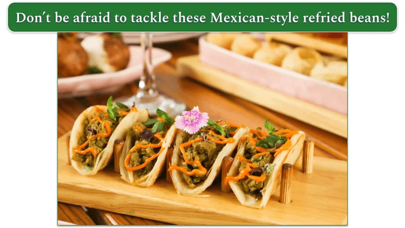 4 tacos on a wooden serving dish with refried beans.