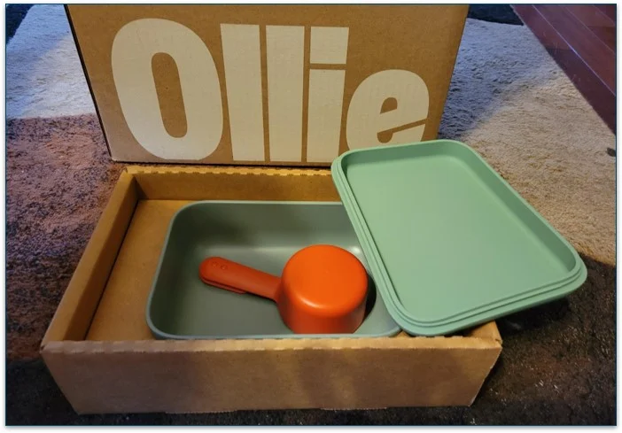 Photo of Ollie's Puptainer and a feeding scoop in a box