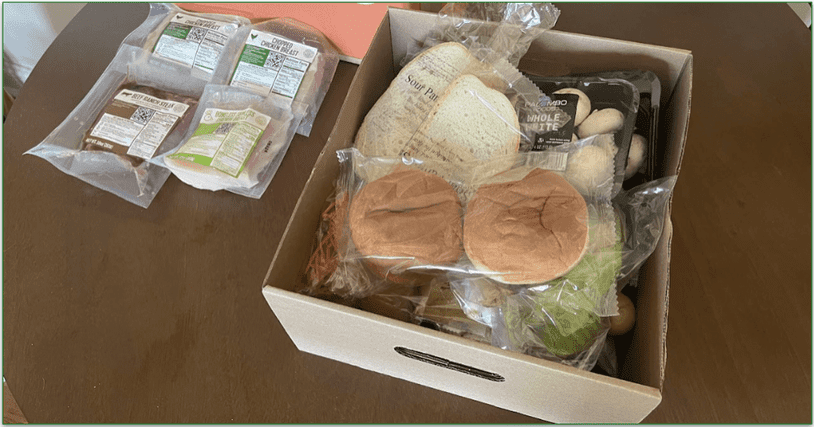 EveryPlate delivery box, packaged meats, and a cardboard tray containing all the ingredients for the recipes