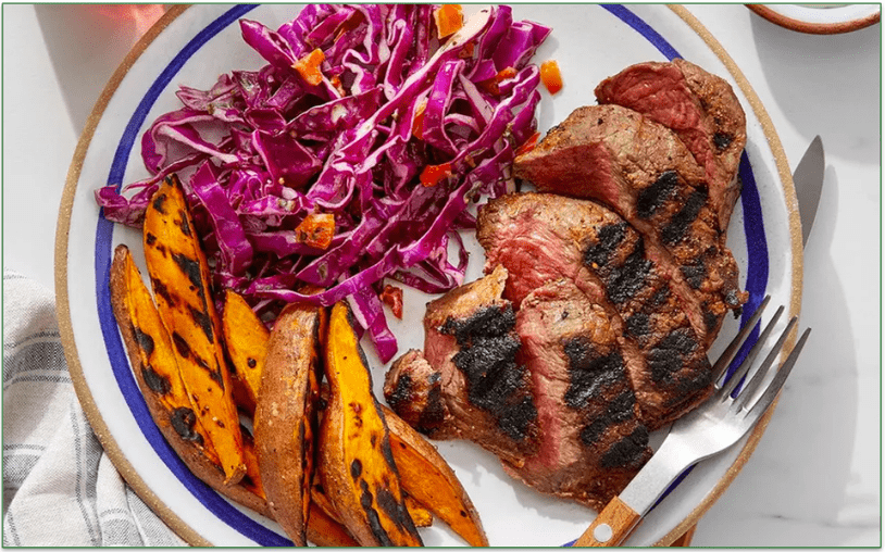 A plate of steak, roasted sweet potatoes, and shredded cabbage.