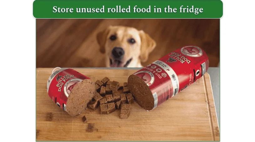 Dog looking up at a chopped rolled food meal on a board