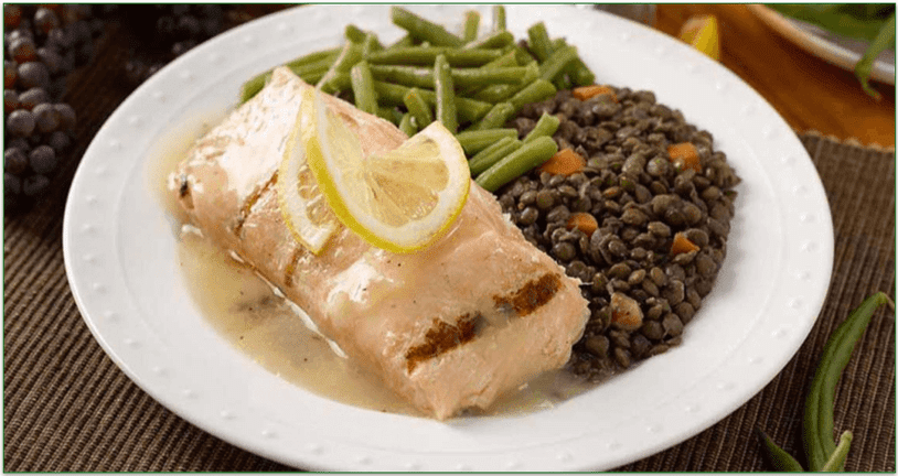 a salmon filet in a light sauce with lentils and green beans