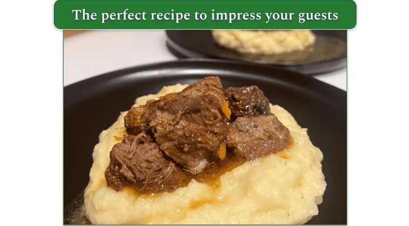 A serving of Beef Burgundy over a bed of mashed potatoes, on a plate