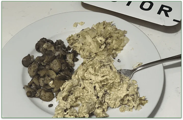 Photo of the Dijon Cream Chicken Thighs on a plate with a fork next to the Factor cardboard sleeve