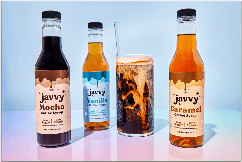 Javvy's 3 syrup bottles next to a glass of coffee with a straw
