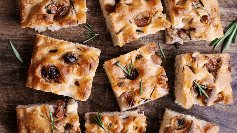 Several pieces of focaccia on a wooden table.