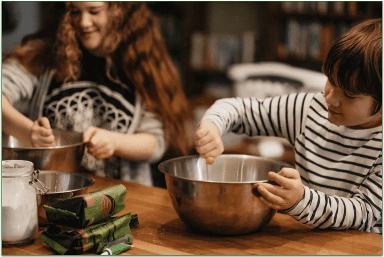 Children stirring mixing bowls at a kitchen counter